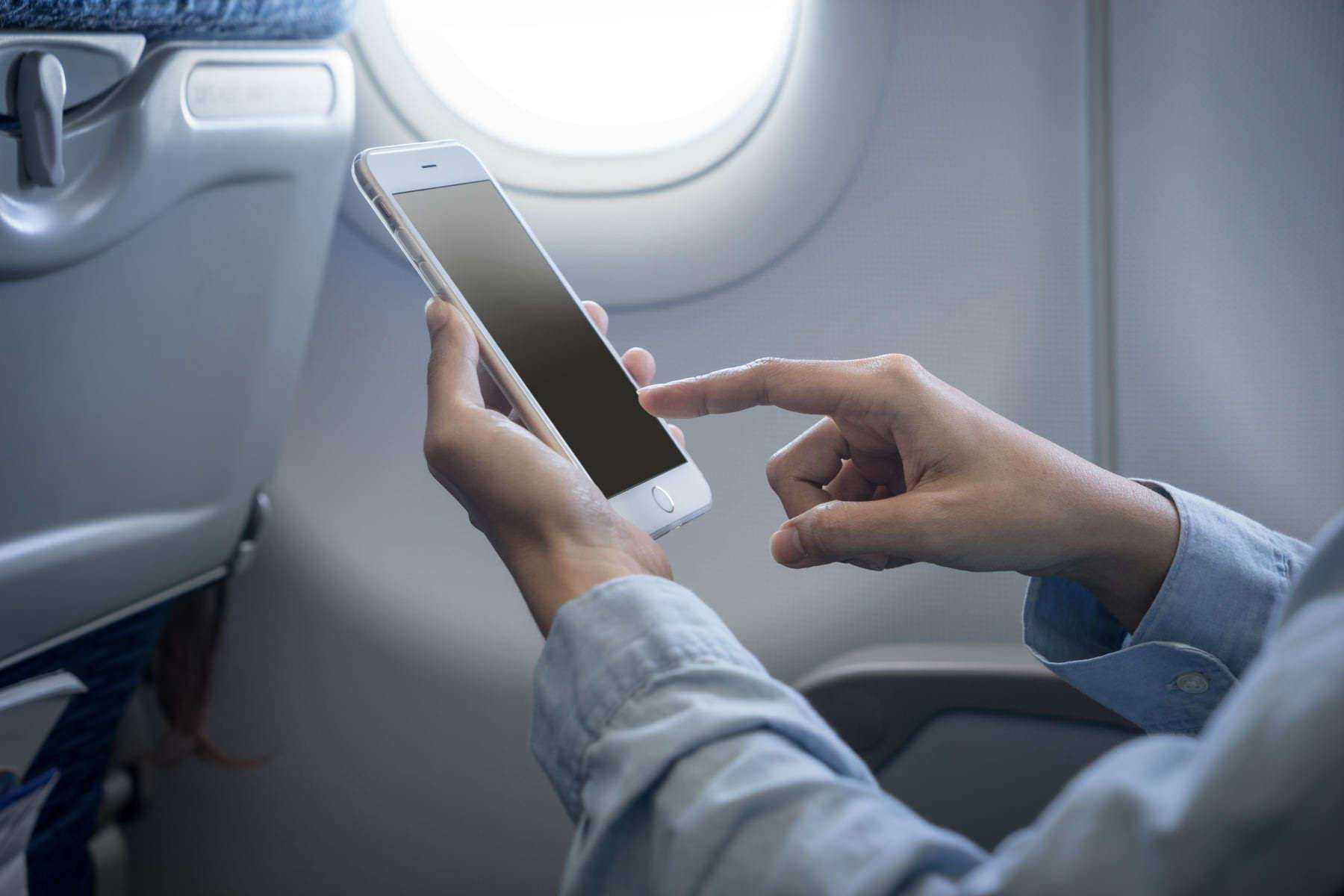 В самолетах можно зарядить телефон. Телефон в самолете. Человек с телефоном в самолете. Телефон в руке. Интернет на борту самолета.