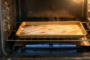 Противень с мукой в духовке газовой плиты для проверки температуры